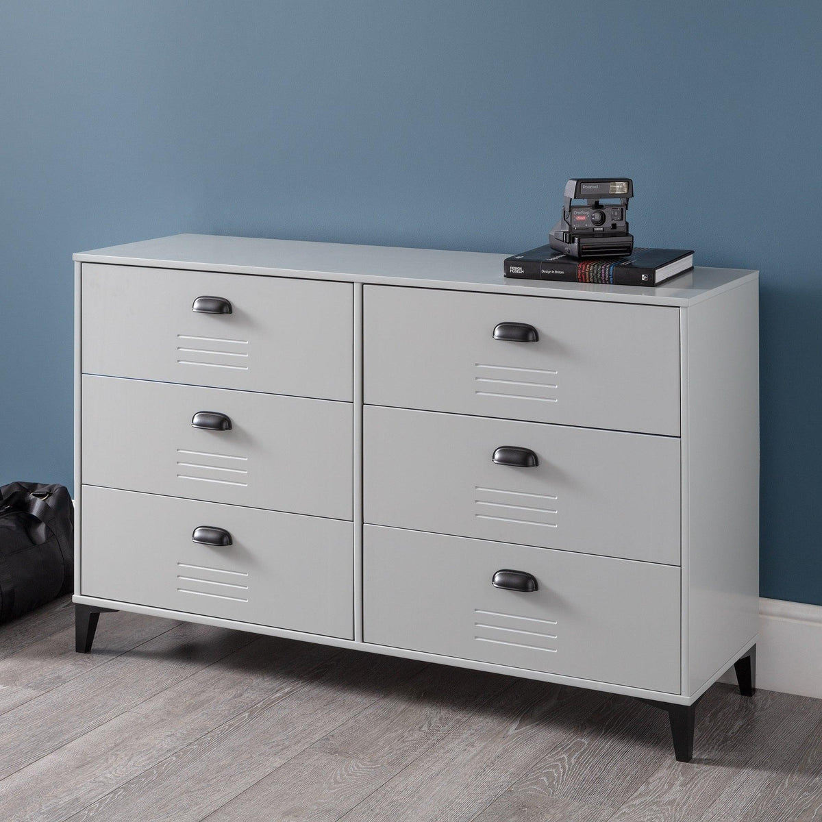 Light grey 6 drawer wide chest with black handles in modern room on wooden floor