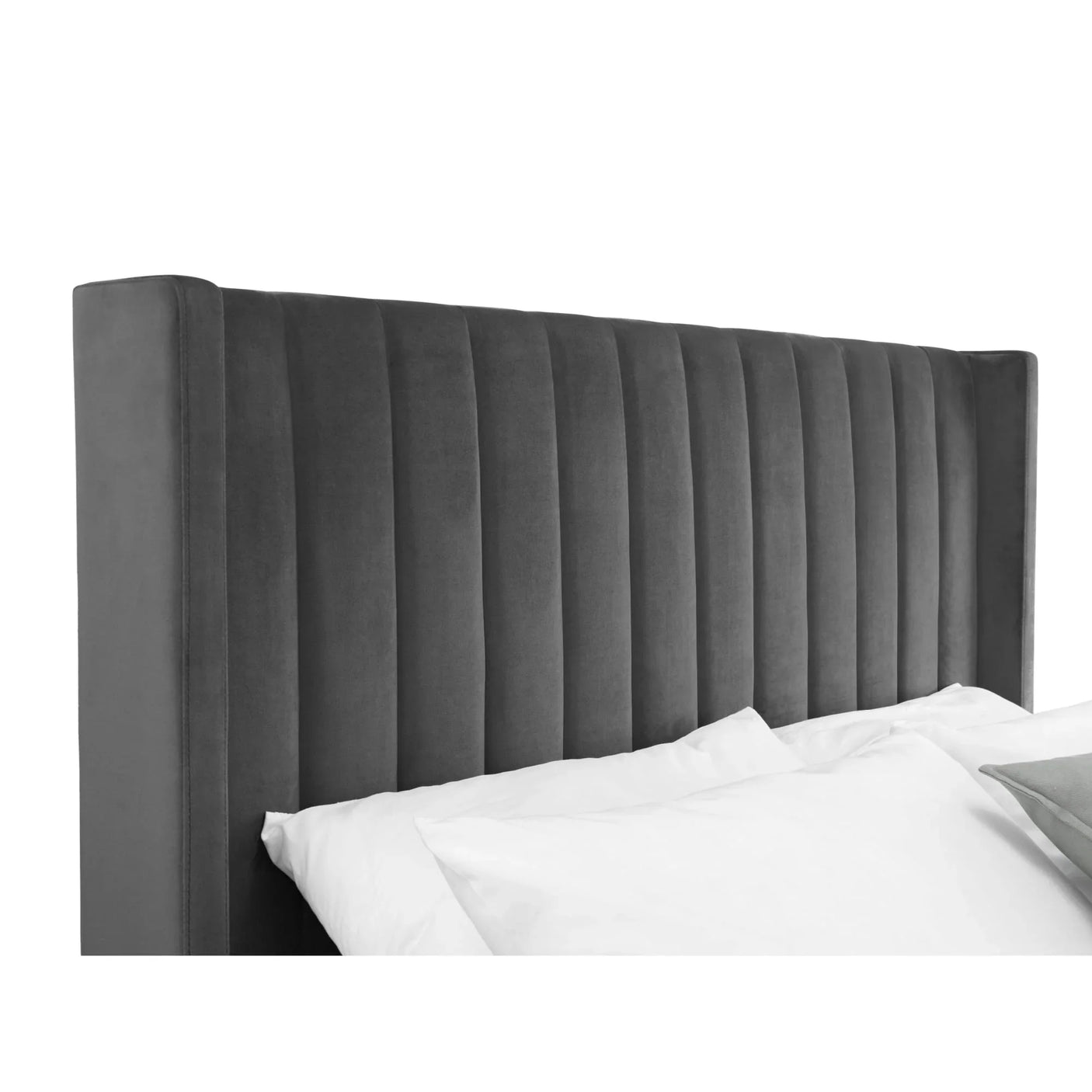 Grey velvet upholstered bed headboard with vertical panel design and pillows