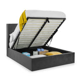 Grey ottoman storage bed with raised slatted base, bedding, and boxes stored underneath