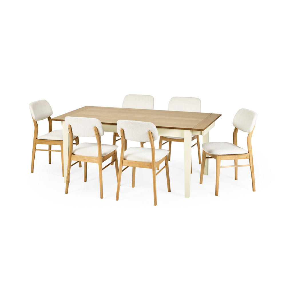 Dining table with cream legs and natural wood top surrounded by six wooden chairs with white cushioned seats.