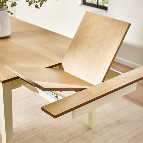 Close-up of table extension mechanism with wooden insert partially lifted, showing metal slide rail