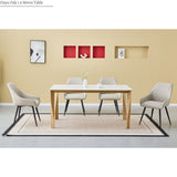 A dining room scene showing a rectangular Oak 1.6 metre table with a light wood finish and four upholstered dining chairs in a light beige color with black legs, arranged on a patterned rug against a beige wall.