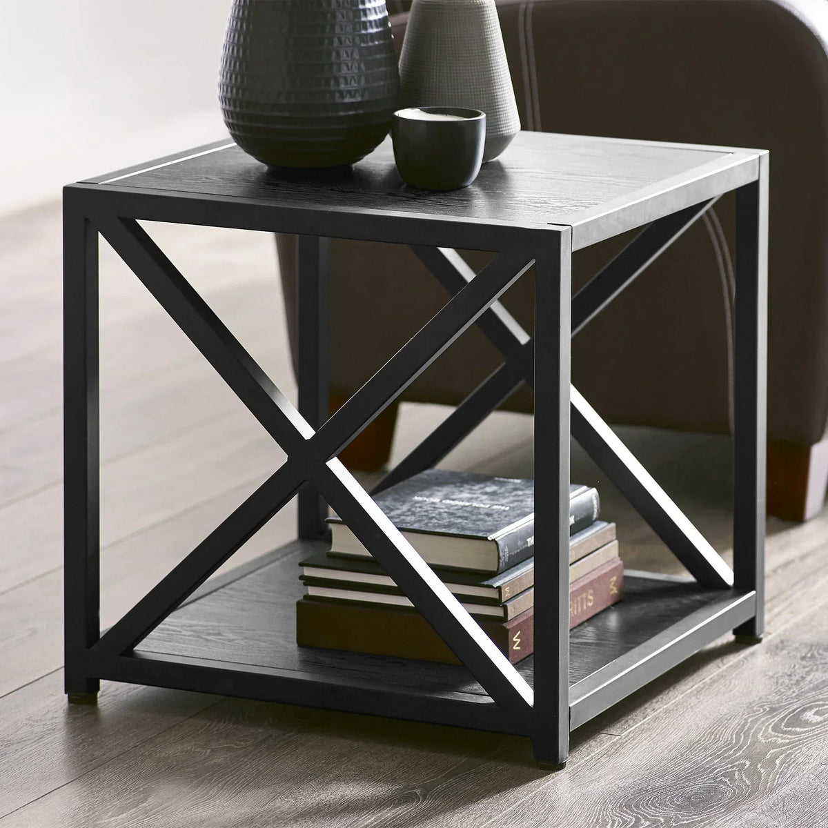 Black metal frame lamp table with decorative vases and books on shelf in living room