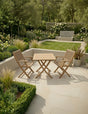 Teak garden dining set with two chairs on tiled patio surrounded by landscaped greenery
