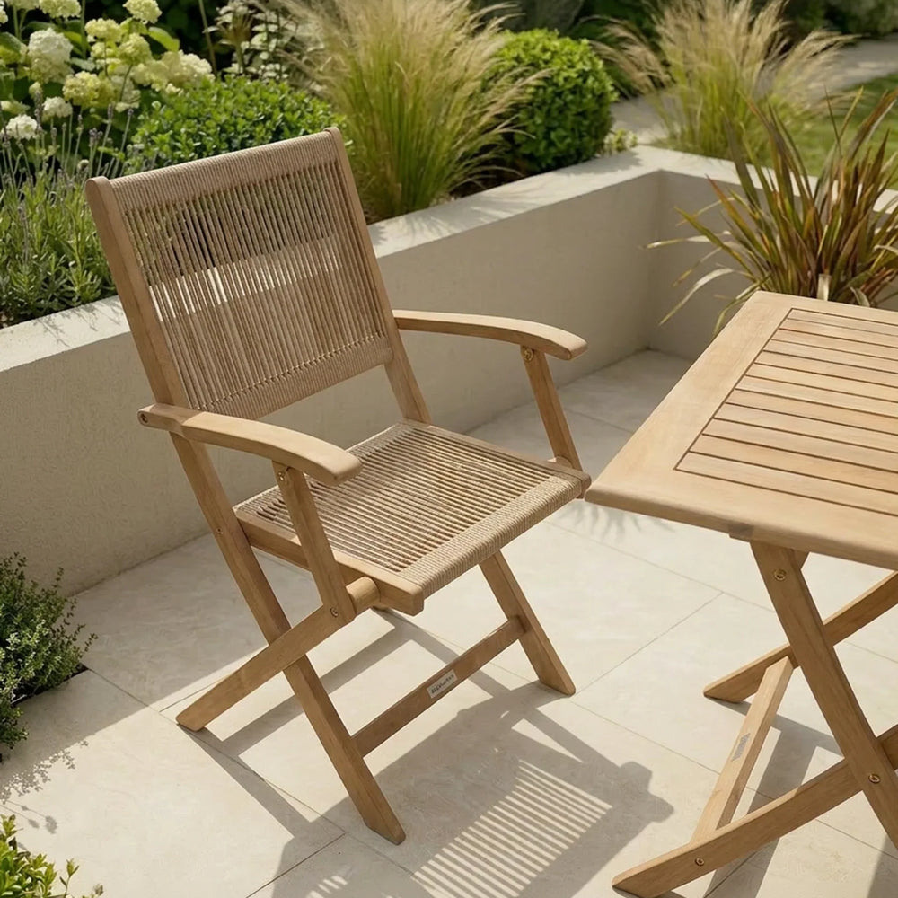 Wooden garden chair and table set on patio with greenery and plants in the background