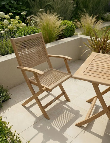Wooden garden chair and table set on patio with greenery and plants in the background