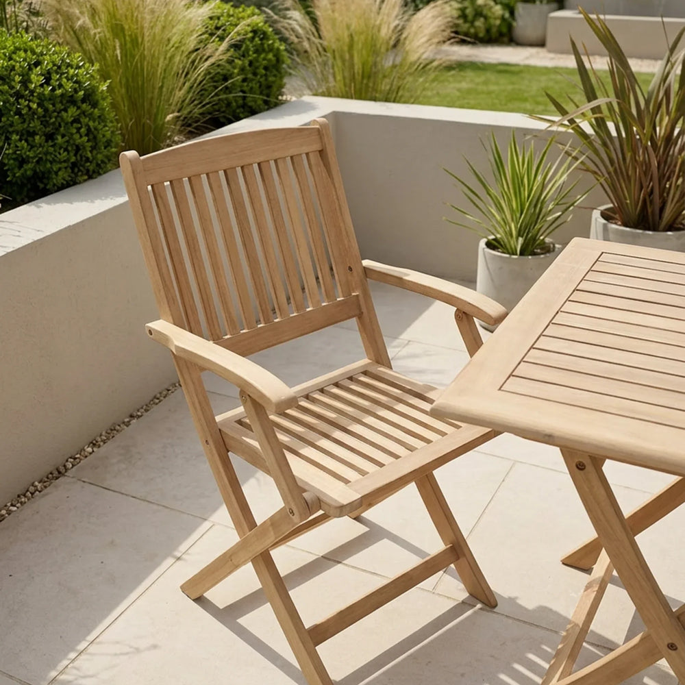 Wooden garden dining chair and table set on tiled patio with plants in background