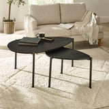 Two black teardrop-shaped nesting coffee tables on fluffy beige carpet in front of beige sofa