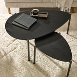 Close-up of black wood teardrop table tops and cylindrical black metal legs on beige carpet