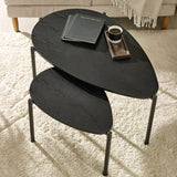 Overhead view of two black teardrop nesting coffee tables on beige carpet with books and coffee cup