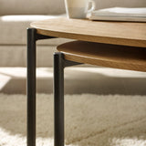 Close-up of light wood teardrop coffee tables with black metal legs, showing layered table tops and details