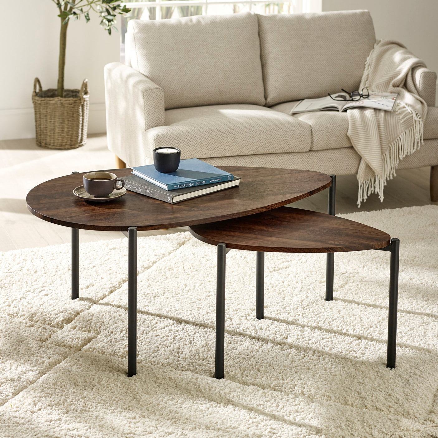 Dark wood nesting teardrop coffee tables with black metal legs in living room on light rug