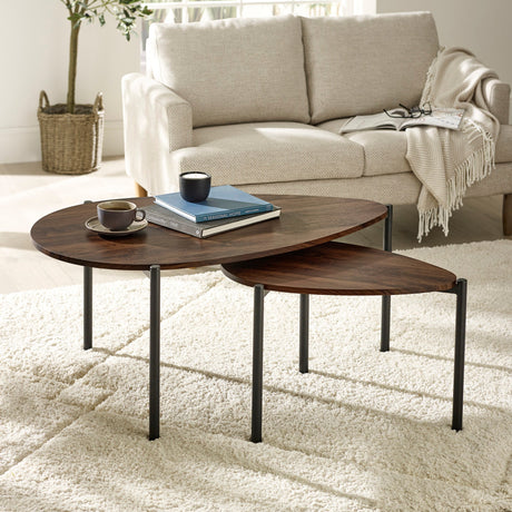 Dark wood nesting teardrop coffee tables with black metal legs in living room on light rug