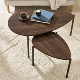 Dark wood teardrop nesting coffee tables with black metal legs in living room, books and cup on top