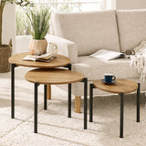 Nesting tables with light wood teardrop tops and black metal legs on cream rug beside sofa.