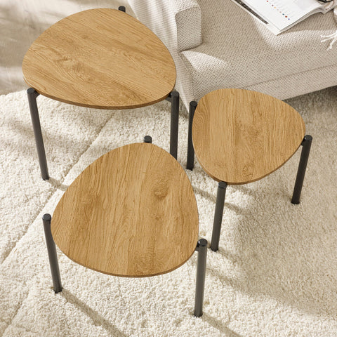 Close overhead view of three teardrop nesting tables on cream rug with coffee cup on smallest table.