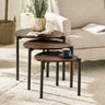Three dark wood teardrop nesting side tables in living room with sofa, plant, book, cup, and soft white rug.