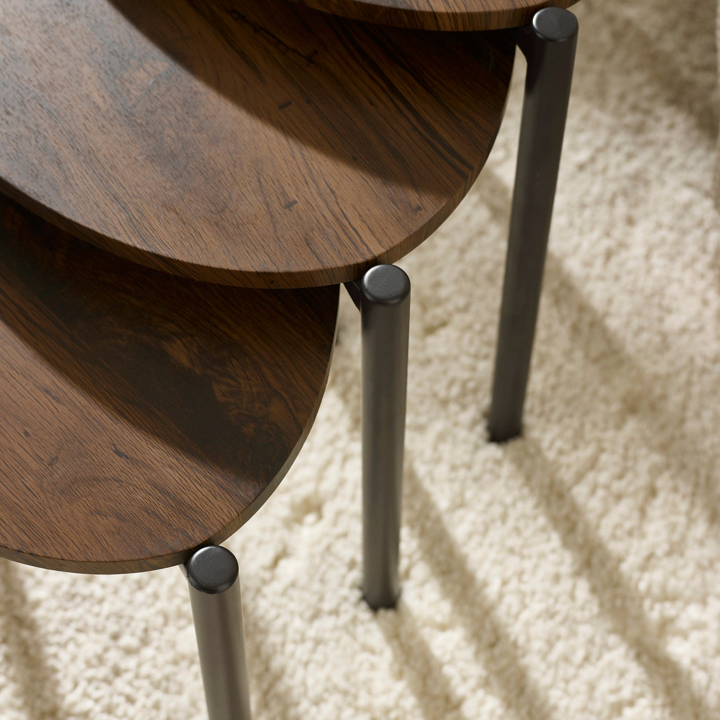 Dark wood teardrop nesting side tables with one holding open book and decorative items, viewed from above.