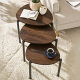 Three dark wood teardrop nesting side tables arranged on white textured rug near light beige sofa and cup of coffee.