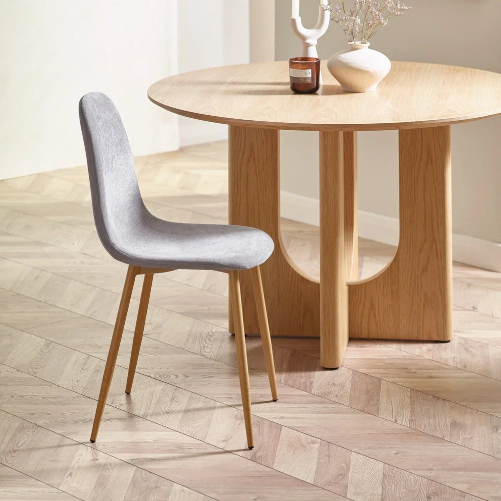 Grey dining chair with wooden legs next to round wooden dining table on chevron floor