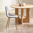 Grey dining chair with wooden legs next to round wooden dining table on chevron floor