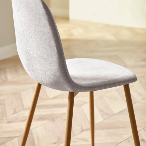 Light grey dining chair with fabric upholstery and wooden legs on herringbone floor