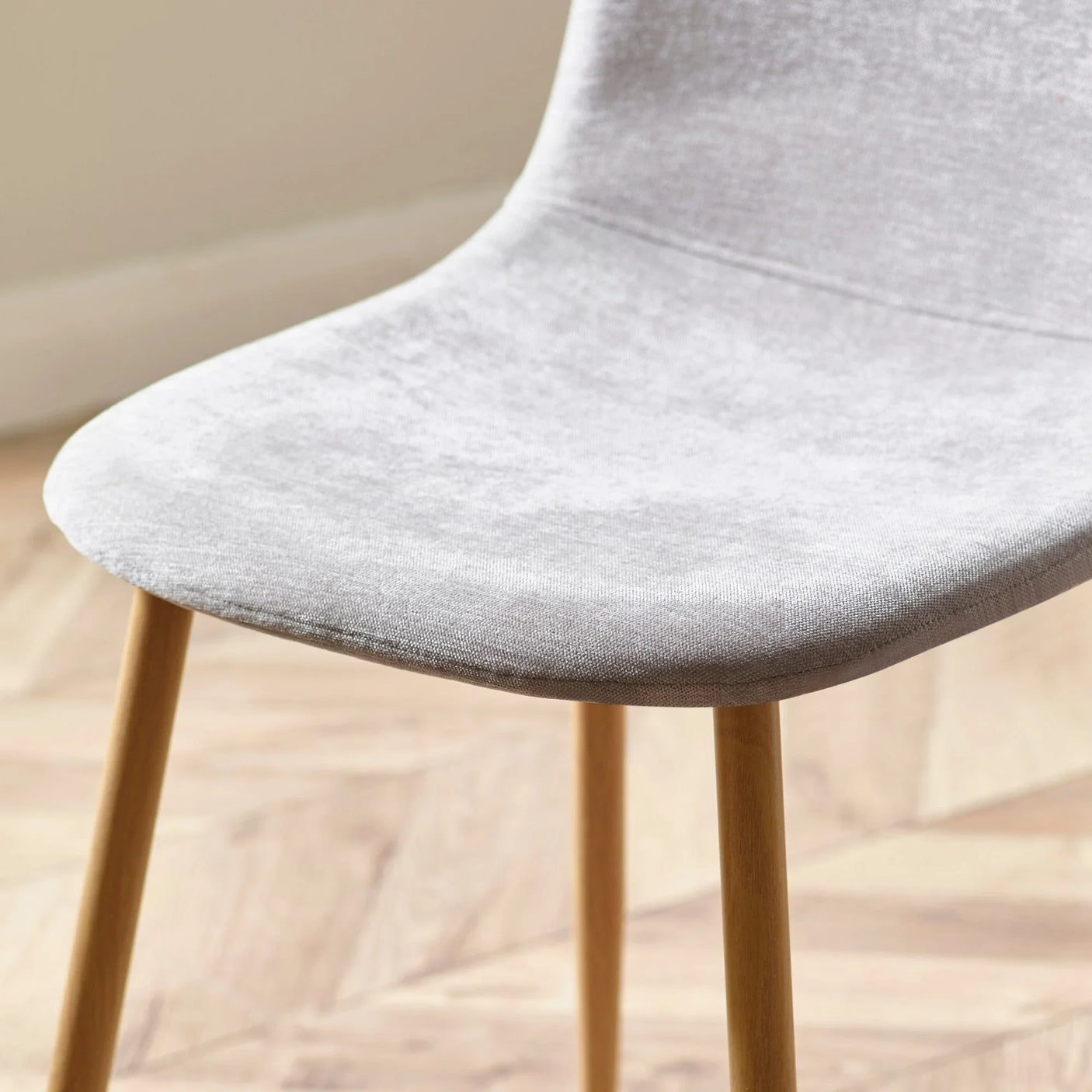 Light grey fabric dining chair with wooden legs on herringbone floor