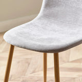 Light grey fabric dining chair with wooden legs on herringbone floor