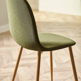 Green upholstered dining chair with wooden legs on herringbone floor