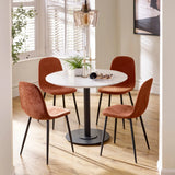 Round dining table with white top and four orange fabric chairs on wood floor