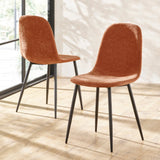 Pair of modern orange velvet dining chairs with black metal legs on wooden floor
