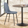 Grey fabric dining chair with black metal legs next to round dining table on wood floor