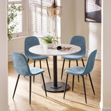 Round dining table with white top and four blue velvet dining chairs on wood floor