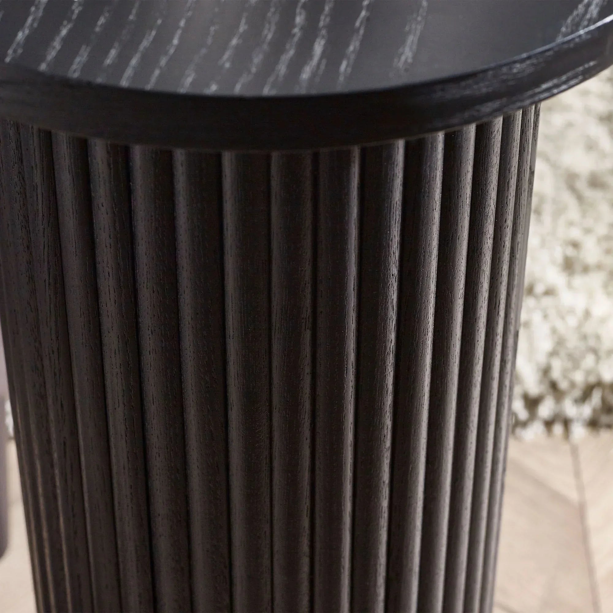Black fluted drinks table with ribbed cylindrical wood base, close-up of textured detail