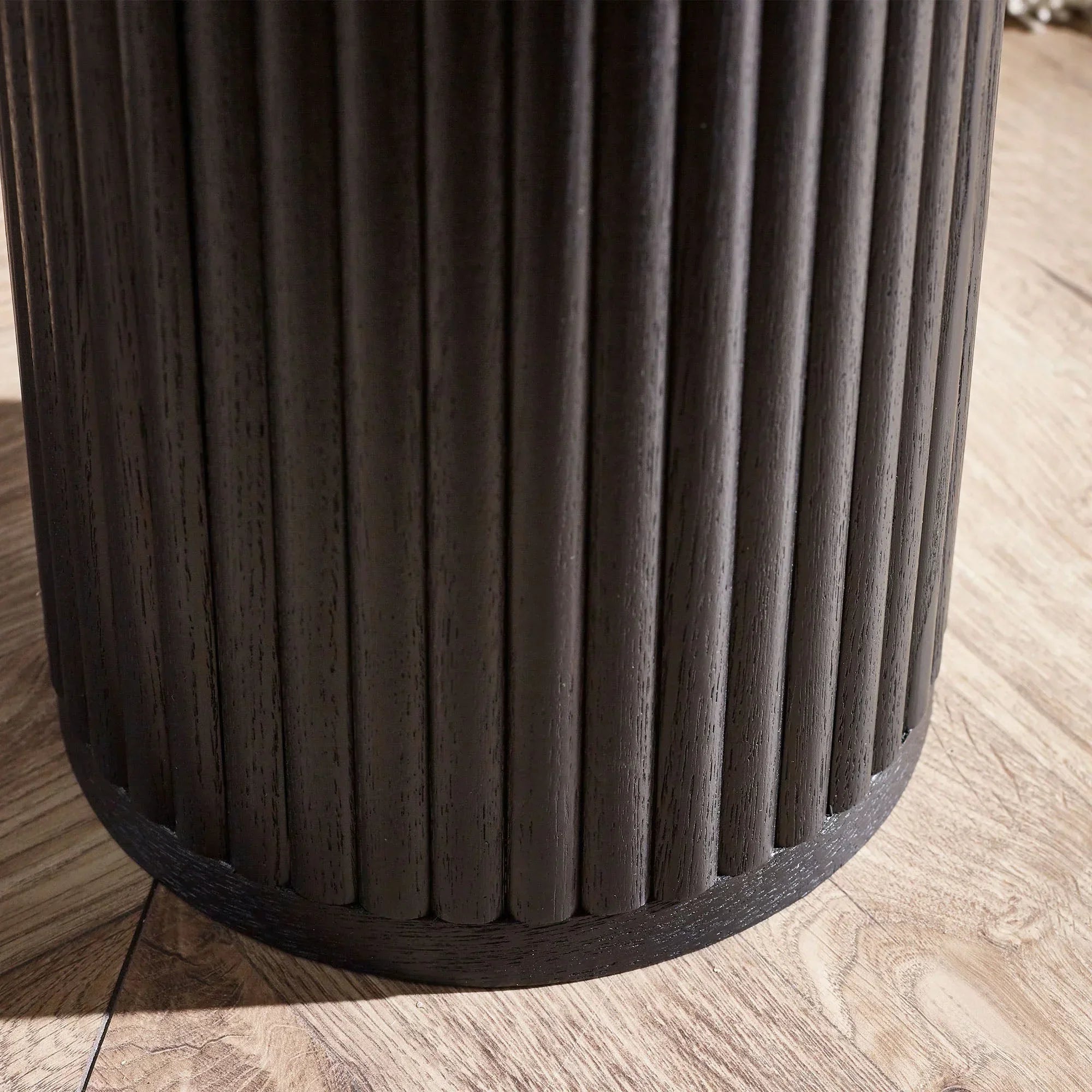 Black fluted drinks table base with ribbed wood detail on light oak floor