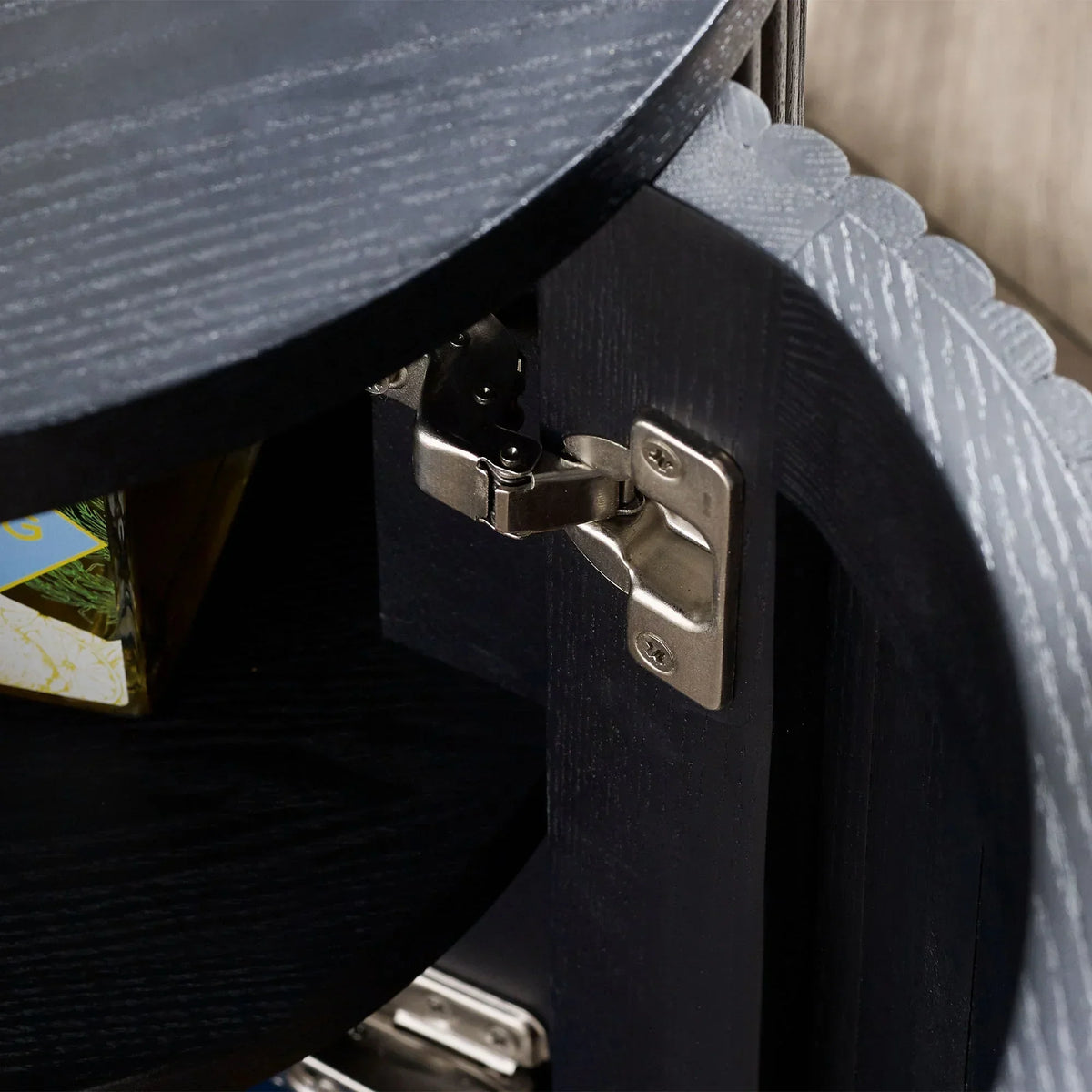 Black fluted side table closeup showing metal door hinge and wood grain detail