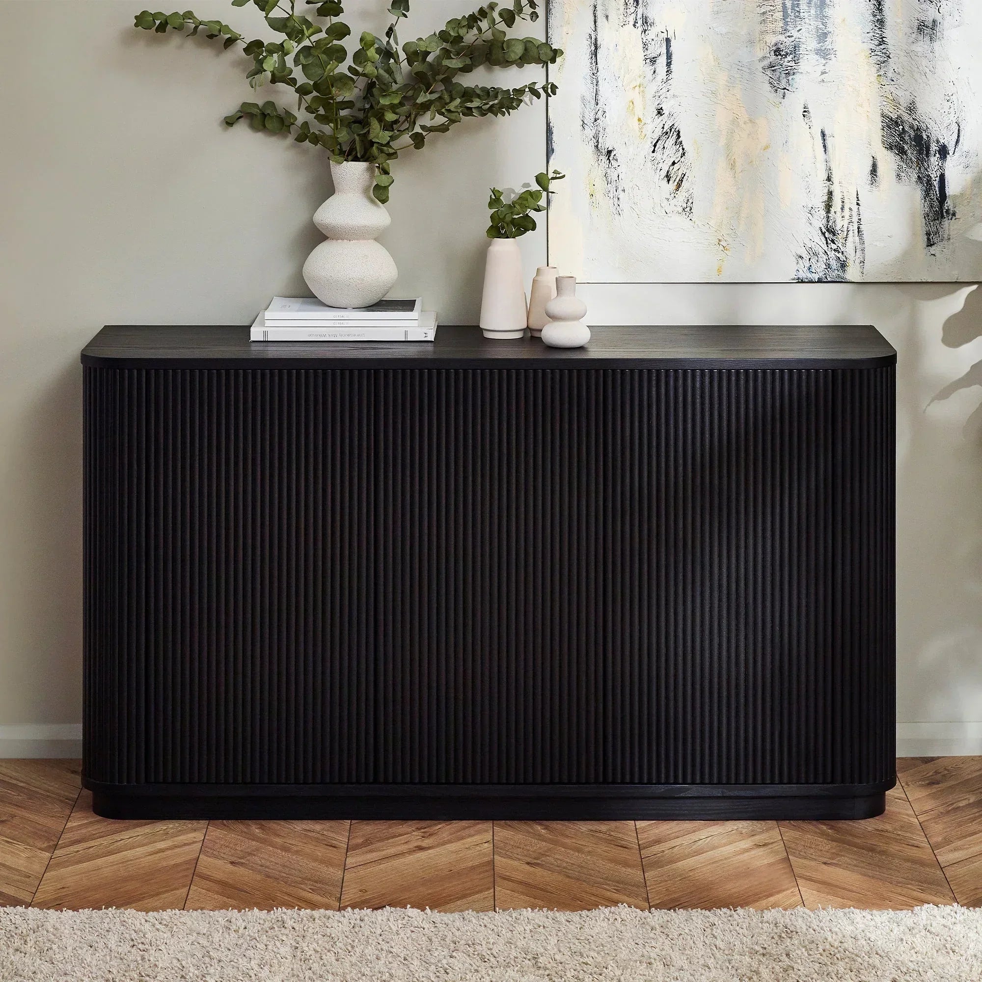Black fluted sideboard with decorative vases in modern living room setting