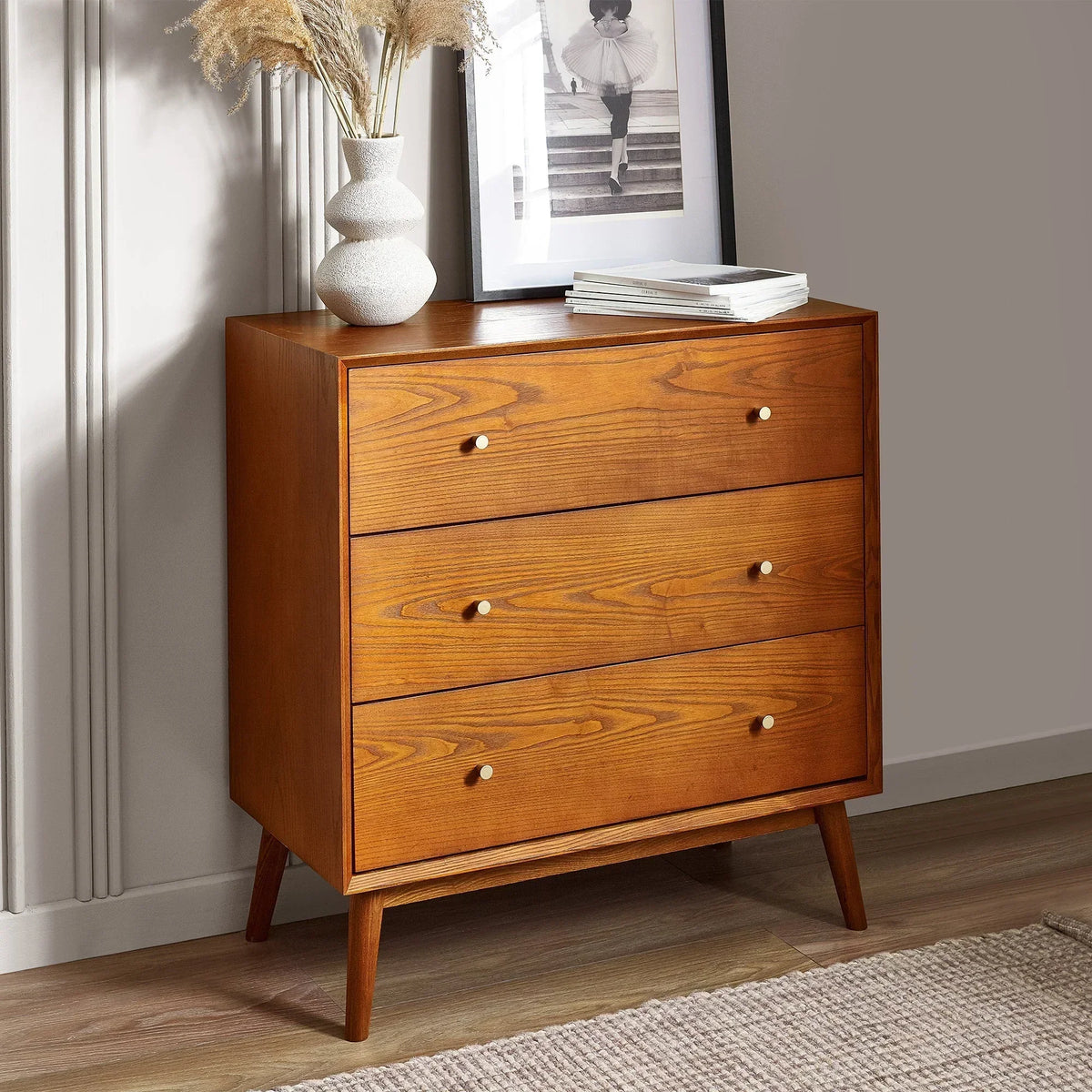 Mid-century wood three drawer chest with white knobs in modern bedroom setting