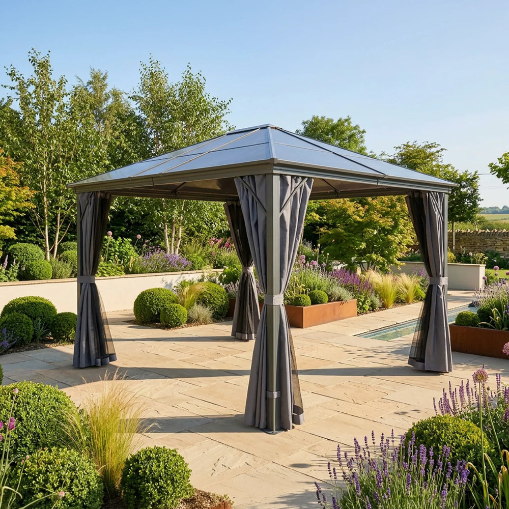 Grey metal garden gazebo with curtains on a stone patio surrounded by landscaped plants