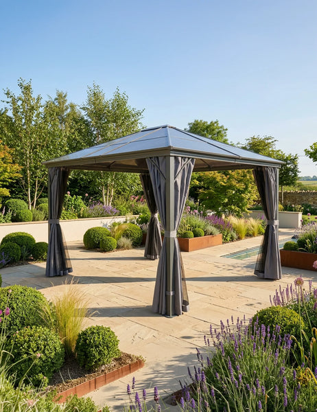 Grey metal garden gazebo with curtains on a stone patio surrounded by landscaped plants