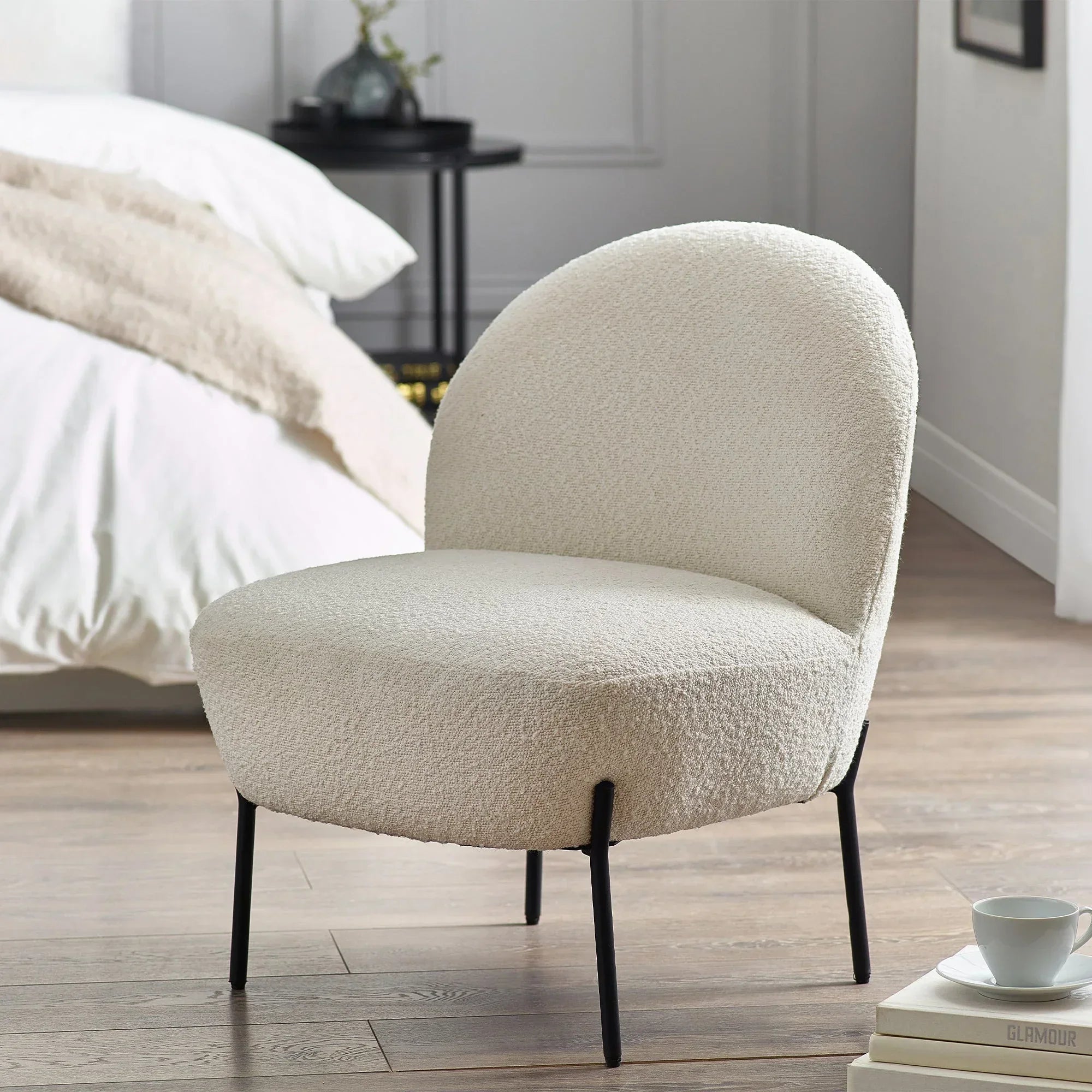 Boucle accent chair with rounded back and black legs in modern bedroom setting