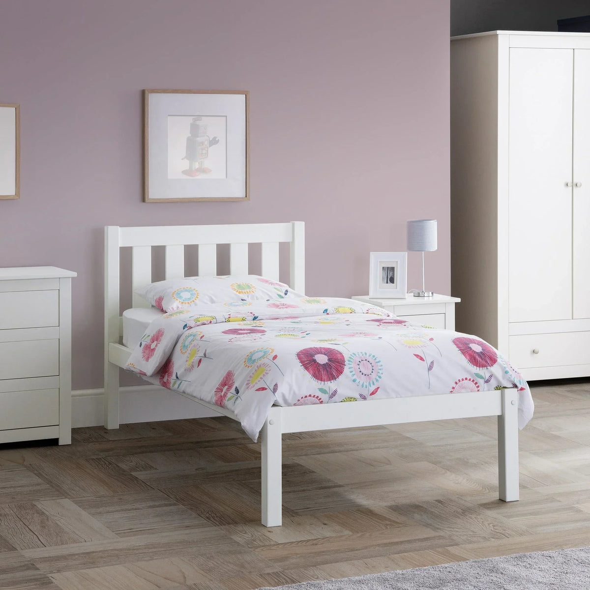 White single bed with floral bedding in a light bedroom with wardrobe and bedside table