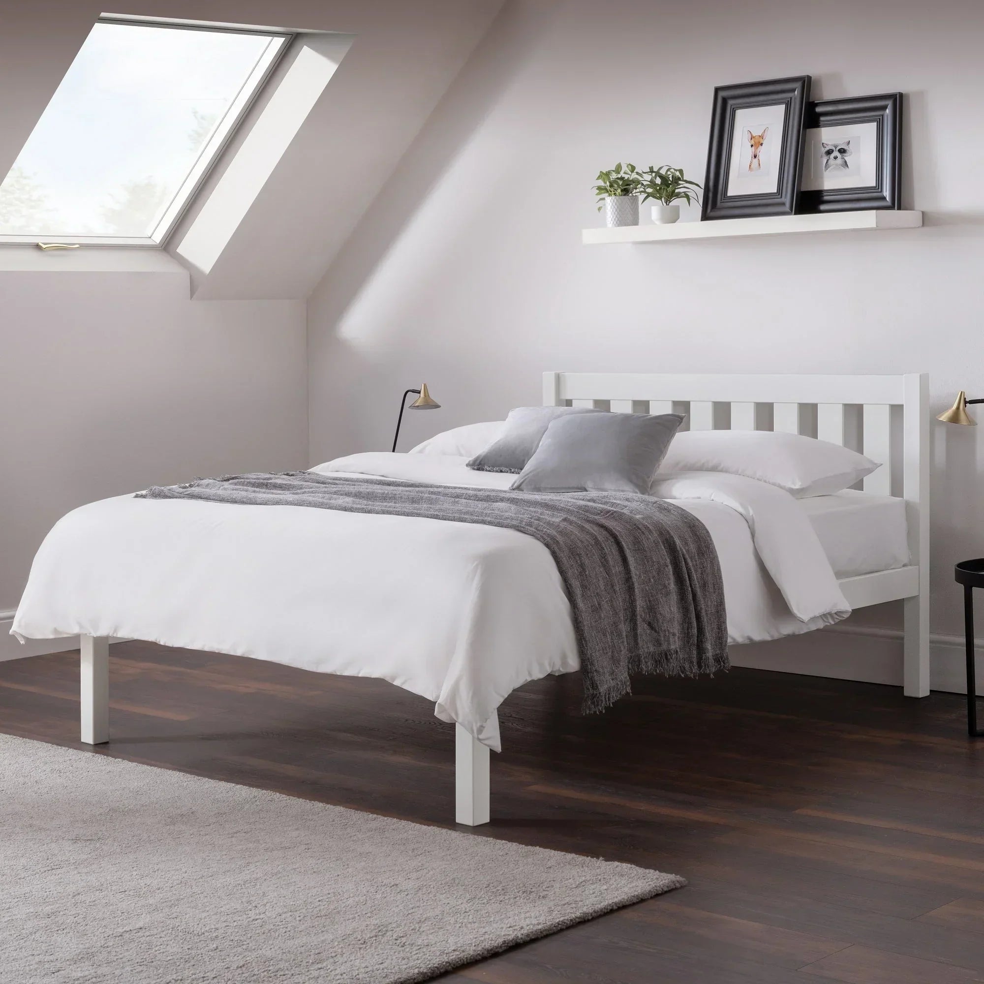 White double bed with slatted headboard, grey throw, and pillows in a modern attic bedroom