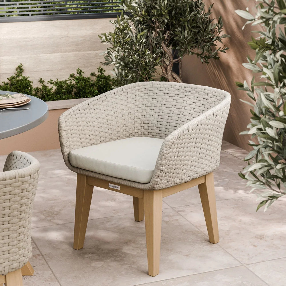 Beige woven outdoor dining chair with cushion on patio near greenery