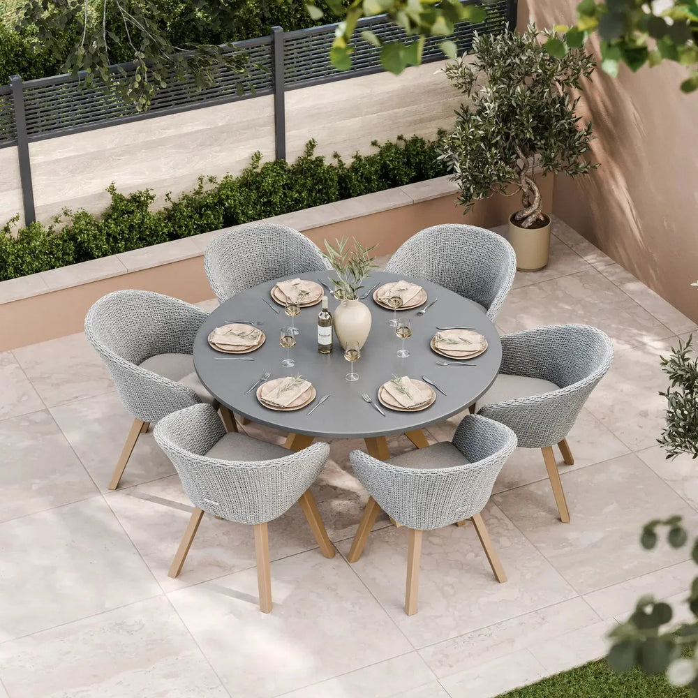 Grey rattan outdoor dining set with round table and six chairs on patio