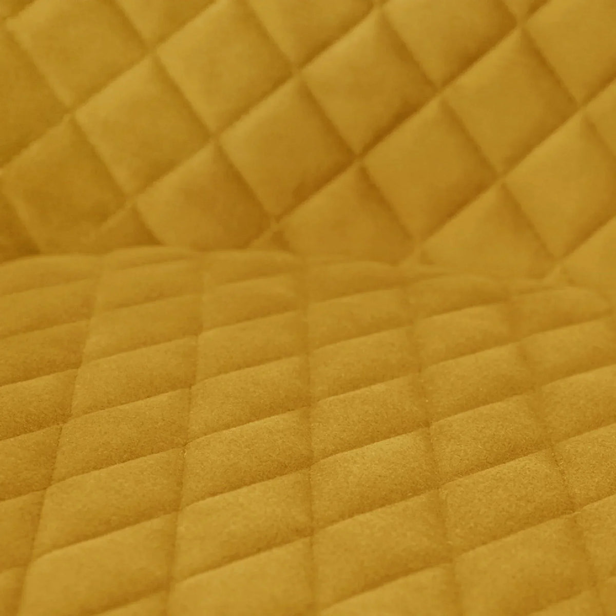 Close-up of mustard velvet dining chair upholstery with diamond quilted pattern