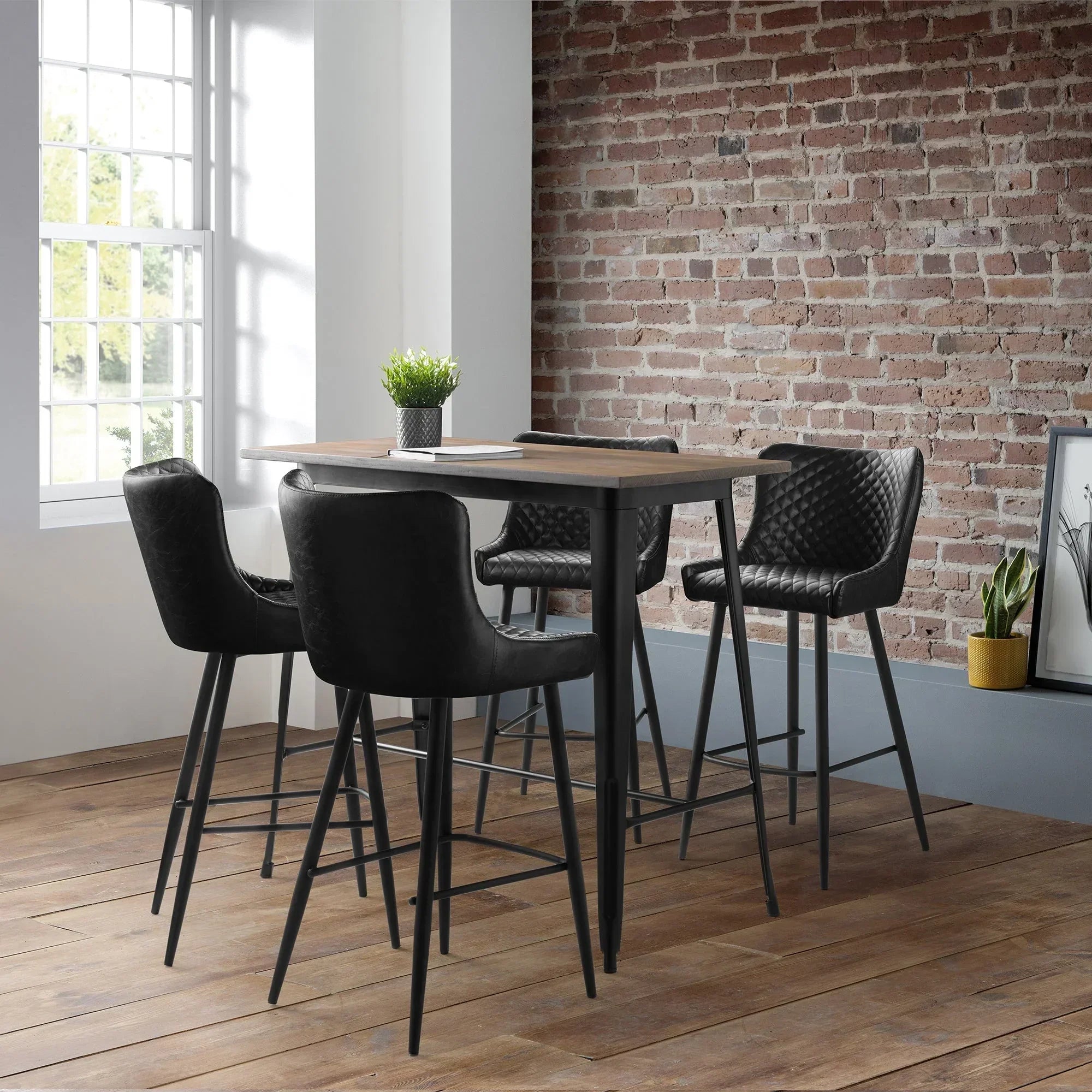 Black faux leather bar stools around wooden high table in modern dining room with brick wall