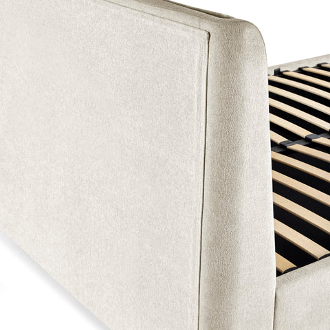 Close-up of beige textured upholstery on bed frame corner with slatted wooden base visible