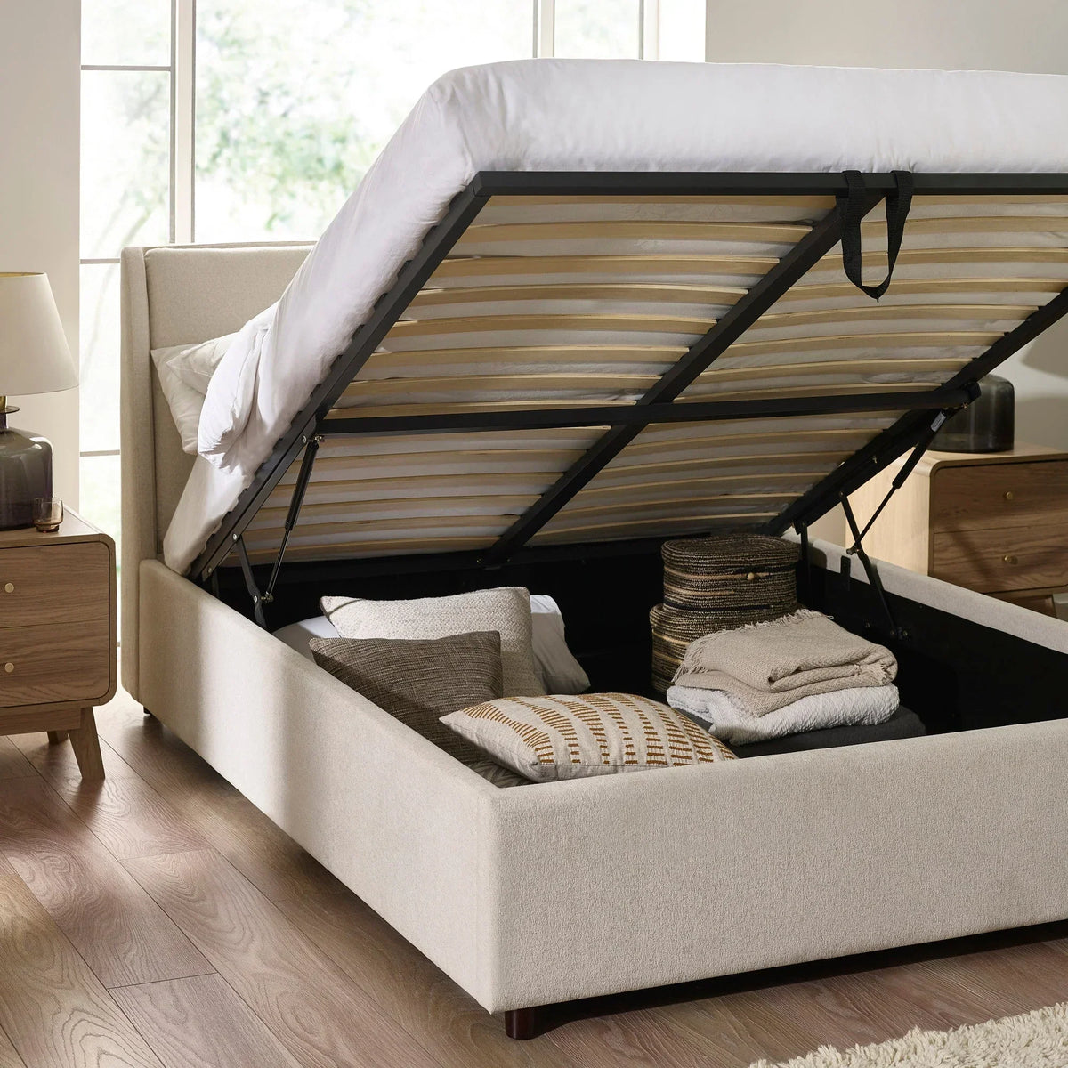 Beige upholstered ottoman storage bed with lifted frame showing underbed storage space