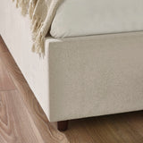 Close-up of beige fabric ottoman bed base corner with wooden leg on wooden floor